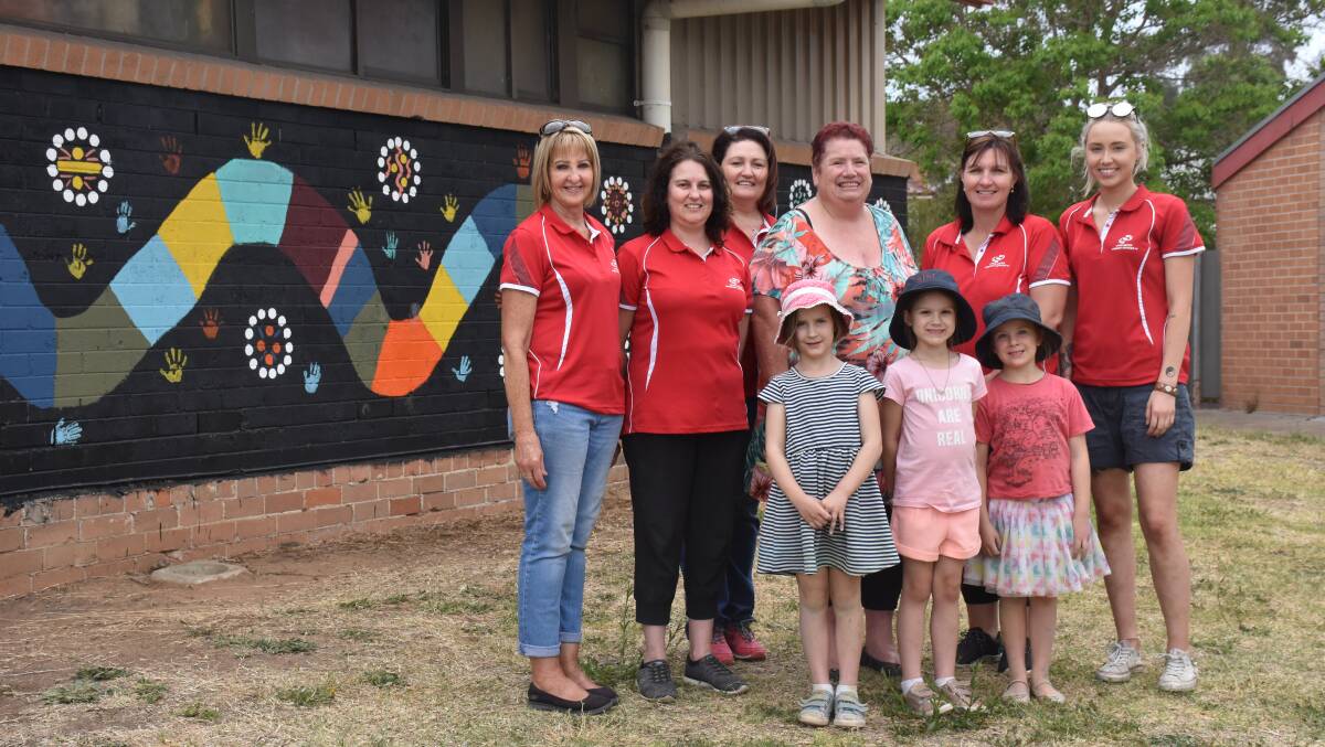 SCHOOL HOLIDAY FUN: MOOSH staff members and children with Wanaruah artist Aunty Denise, with their colourful mural.