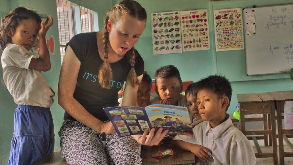 GREAT EXPERIENCE: Grayson Tilse reading to some children in Cambodia.