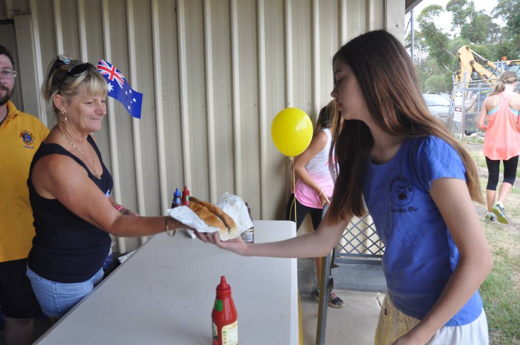TASTY FEED: Margelle Watts hands Chelsea Jones, 12, a sausage sandwich on Sunday.