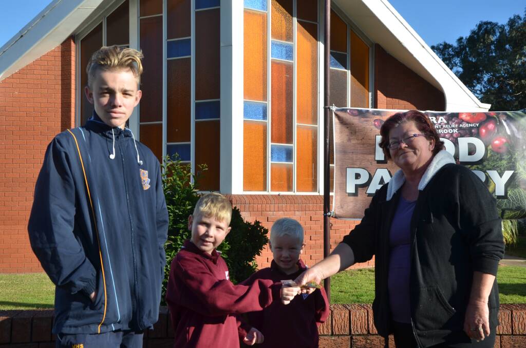 GENEROUS GESTURE: The Dever boys - Harley, 16, Zane, 7, and Khi, 5 - hand over a donation to Muswellbrook's ADRA food pantry coordinator Laurene Edwards during the week.