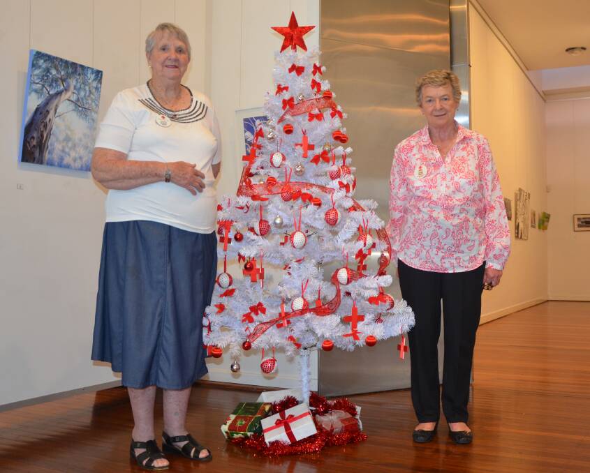 FESTIVE: Muswellbrook Red Cross’ Doreen Scriven and Diane Smith at Muswellbrook Art Gallery with the Red Cross Christmas Tree on display.