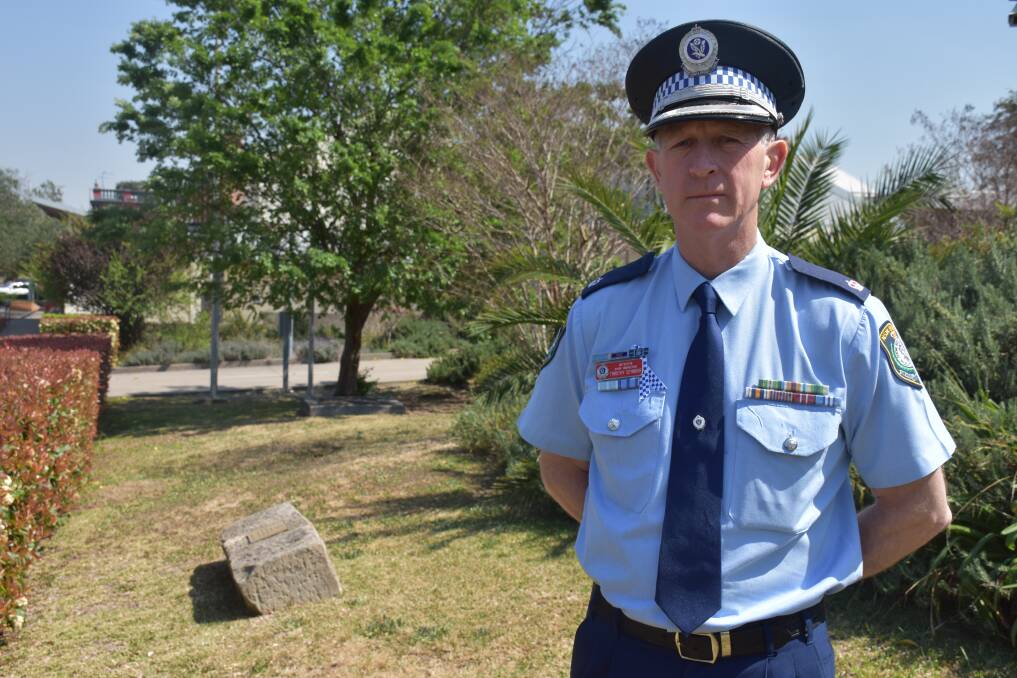 A TIME TO REFLECT: Hunter Valley LAC Detective Chief Inspector Timothy Seymour. Behind him, a plaque outside Muswellbrook Police Station honouring those who have fallen.