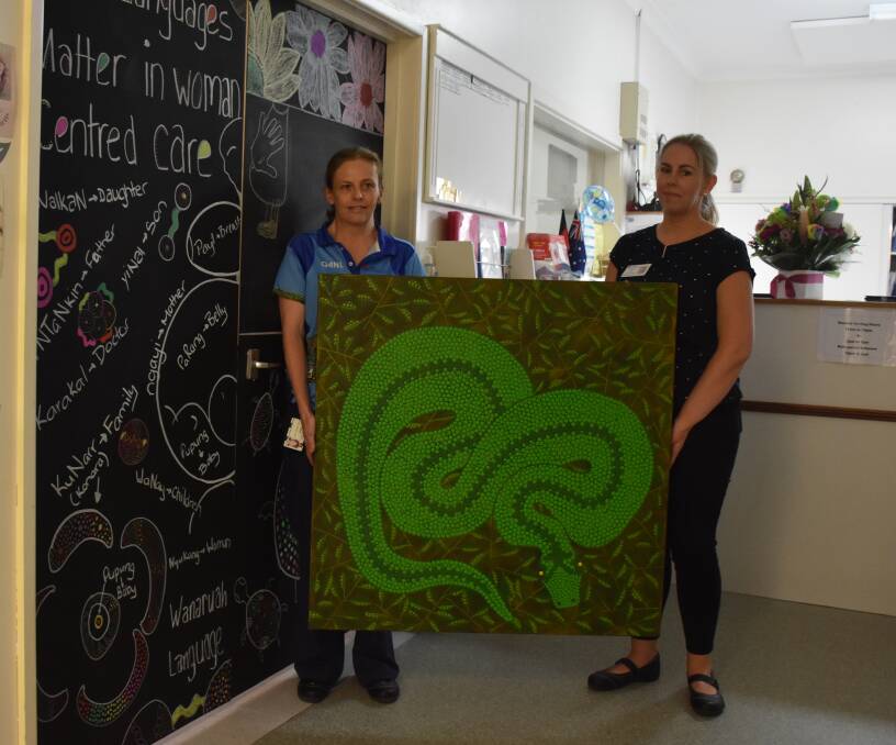 ARTISTIC: Aboriginal health worker Charli Thomas and AMIHS midwife Mandy Hendy with the winning door and gifted artwork by Lesley Salem.