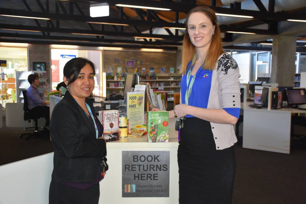 HERE TO HELP: Muswellbrook library's Angelynn Gill and Lauren Allen with some of the items donated through the Food for Fines program.