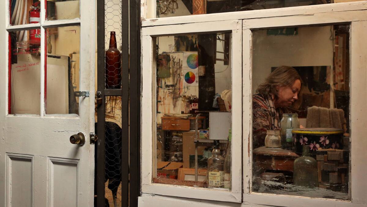 Looking through an internal window to Nicole Chaffey at work in her studio. Picture: Simone De Peak