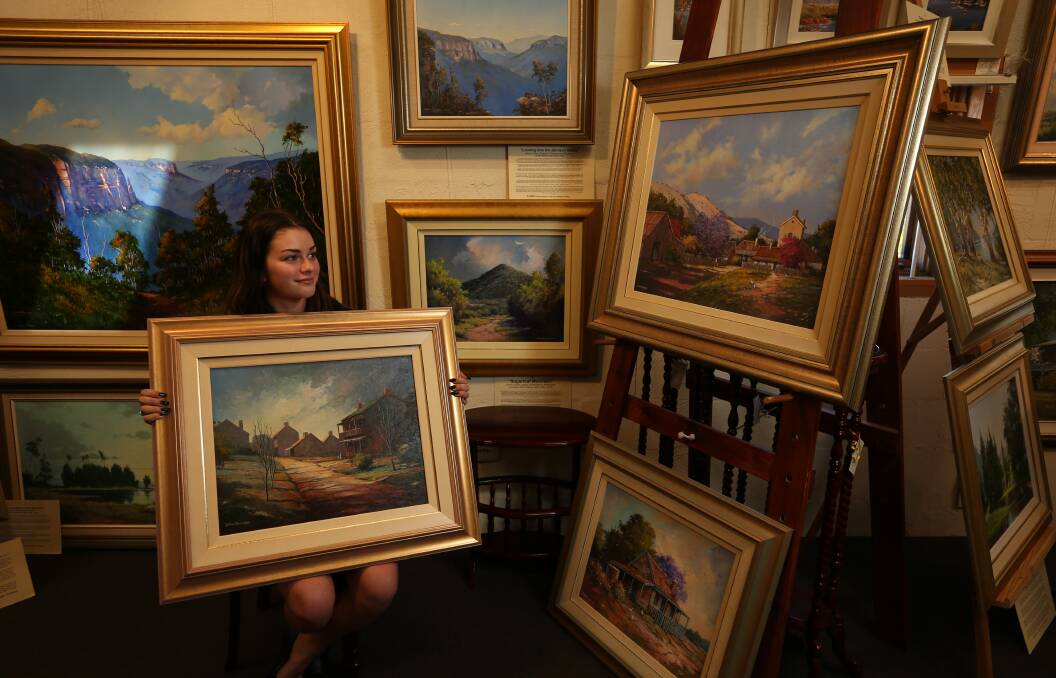 FREEMAN'S WORLD: Morpeth Gallery staff member Tyla Sweeting surrounded by Bill Freeman paintings. Picture: Simone De Peak