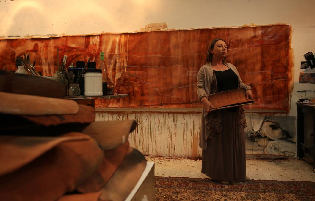 STUDIO: Nicole Chaffey holding clay bowls, with her drawing done in ink made from stringybark. Pictures: Simone De Peak
