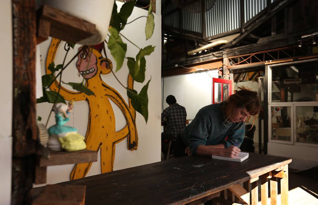 Ellie Hannon working near the kitchen, with a painted sculpture by Michael Bell in the background. Picture: Simone De Peak