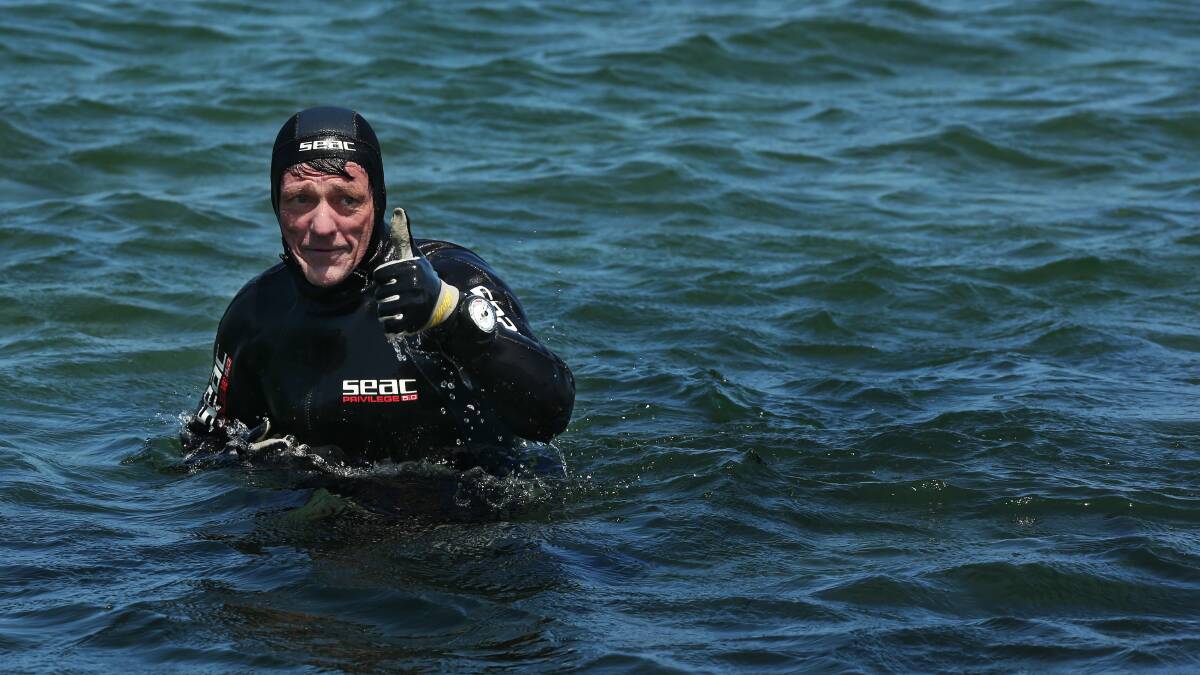 TRIUMPHANT: Swansea Heads man Rod Moore emerges from Lake Macquarie, after walking along the bottom for three kilometres from Marks Point to Belmont in October to raise money for an orphanage in Bali . Picture: Simone De Peak